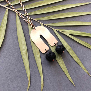 Black lava bead dangles from bronze arch necklace by Red Door Metalworks 